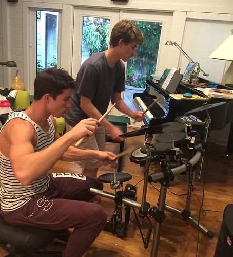 Two students at a piano and drum kit